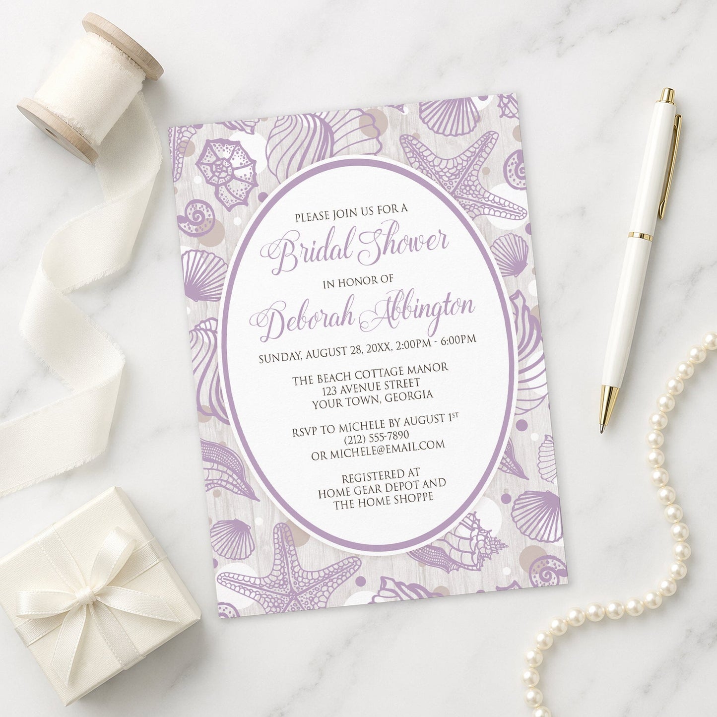 Purple Seashell Whitewashed Wood Beach Bridal Shower Invitation shown on a marble surface with a white gift box, pen, ribbon, and pearls.