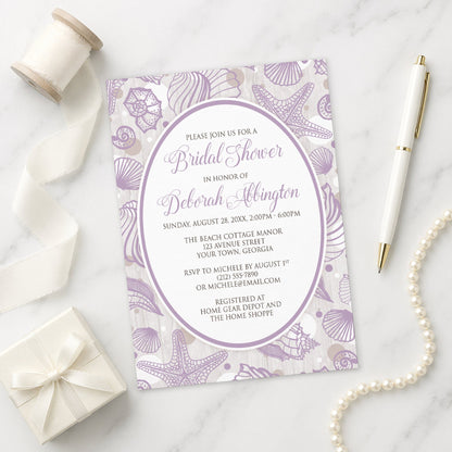 Purple Seashell Whitewashed Wood Beach Bridal Shower Invitation shown on a marble surface with a white gift box, pen, ribbon, and pearls.