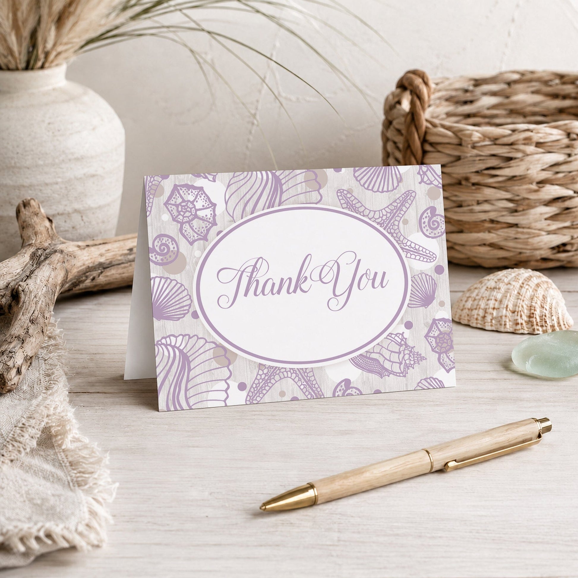 Purple Seashell Whitewashed Wood Beach Thank You Card shown on a beach house tabletop with coastal decor and a pen.