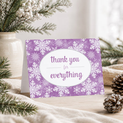 Purple Snowflake Winter Thank You Card shown on a tabletop with a vase, winter greenery, and pine cones.