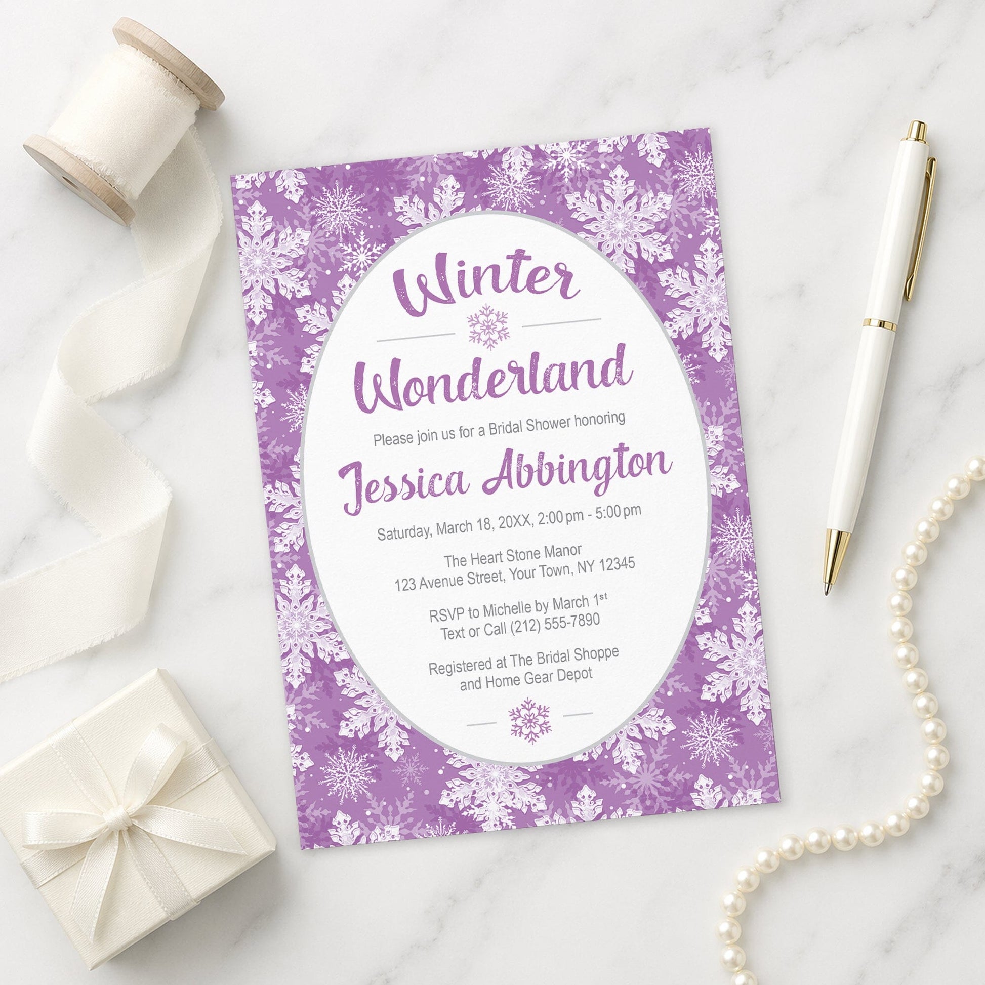 Purple Snowflake Winter Wonderland Bridal Shower Invitation shown on a marble surface with a white gift box, pen, ribbon, and pearls.