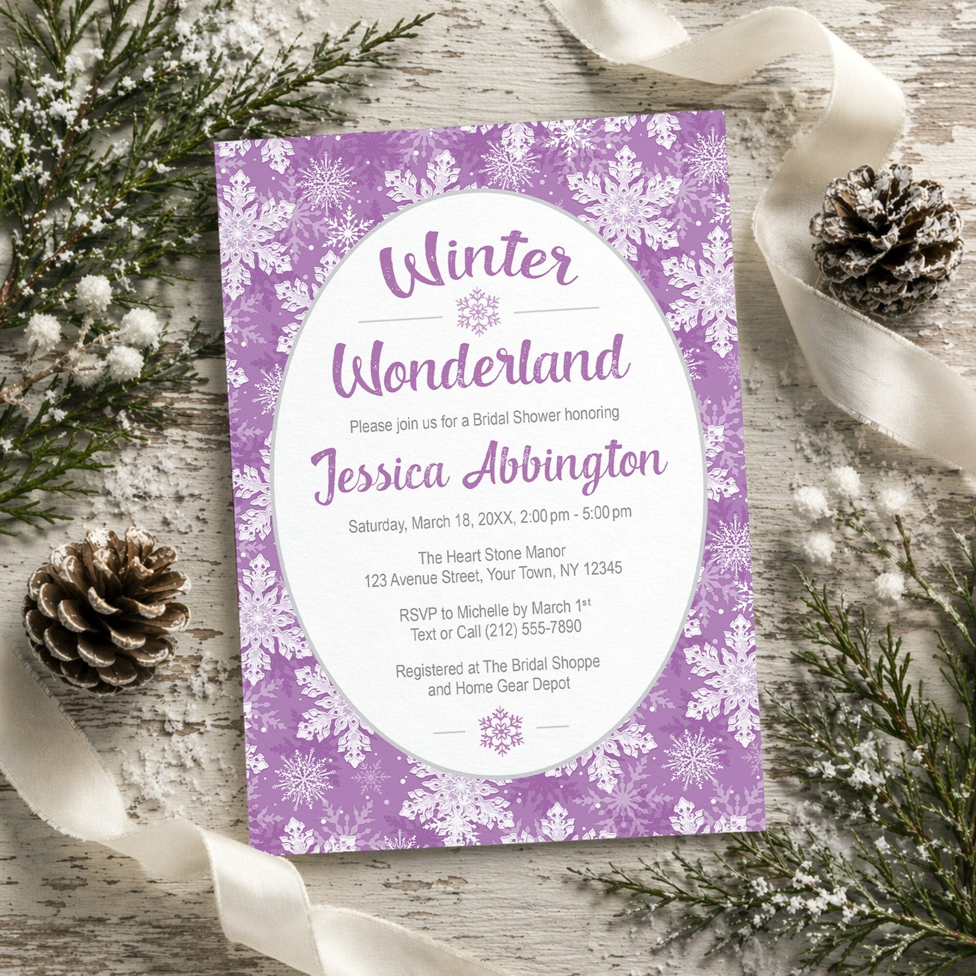 Purple Snowflake Winter Wonderland Bridal Shower Invitation shown on a rustic painted wooden surface with winter greenery, pine cones, and ribbons.