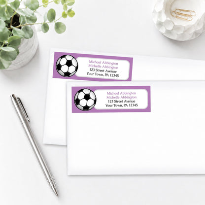 Purple Soccer Ball Address Labels on white envelopes, shown on a white surface with a plant and a pen.