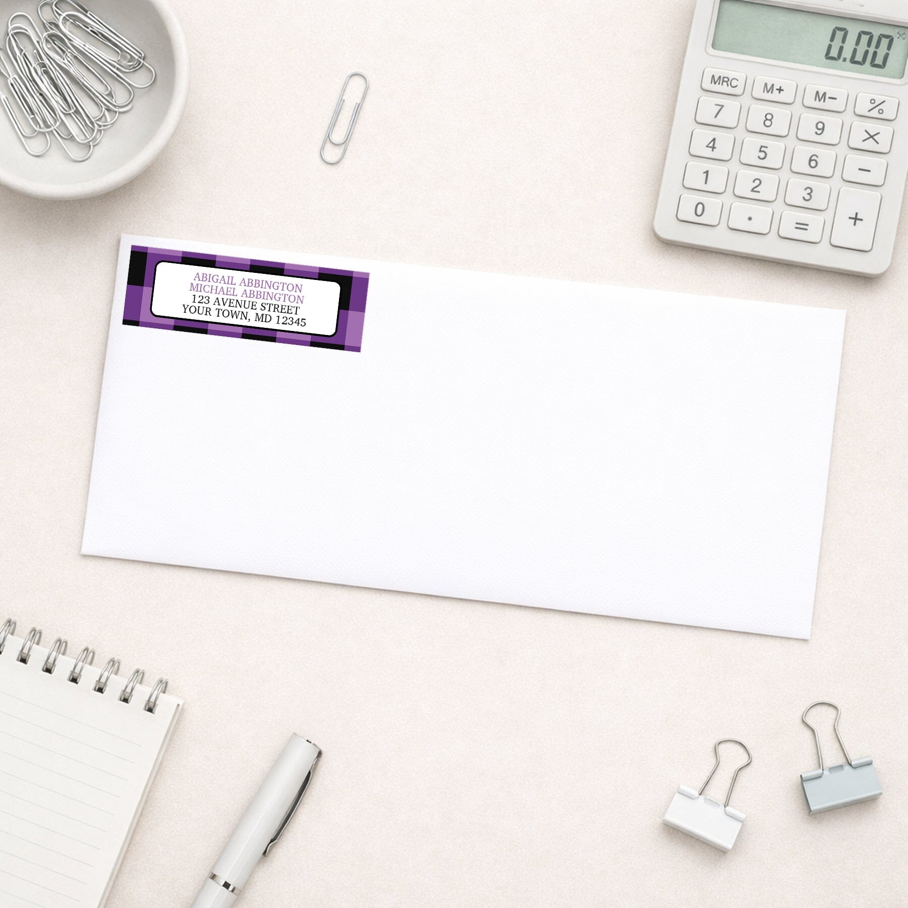 Purple and Black Buffalo Plaid Address Label shown on a white envelope with everyday office supplies