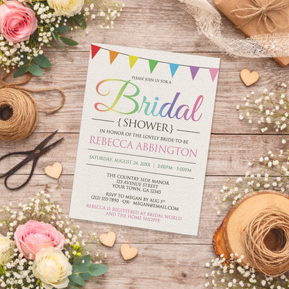 Rainbow Bunting Flags Rustic Bridal Shower Invitation shown on a country-inspired wooden surface with spring and summer flowers, small wood hearts, lace ribbon, and twine.