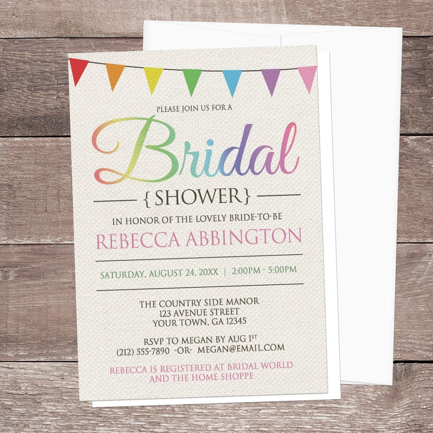 Rainbow Bunting Flags Rustic Bridal Shower Invitation shown on a wooden surface with a white envelope.