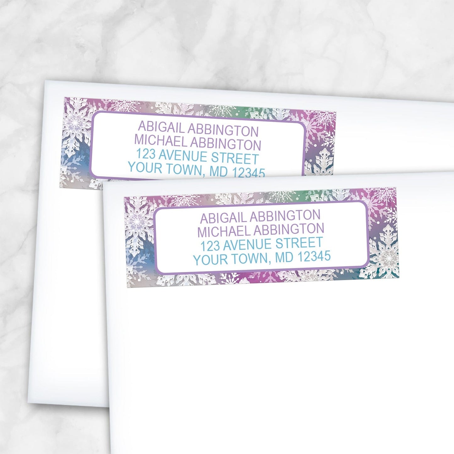 2 Rainbow Snowflake Winter Return Address Labels shown on white envelopes on a marble surface