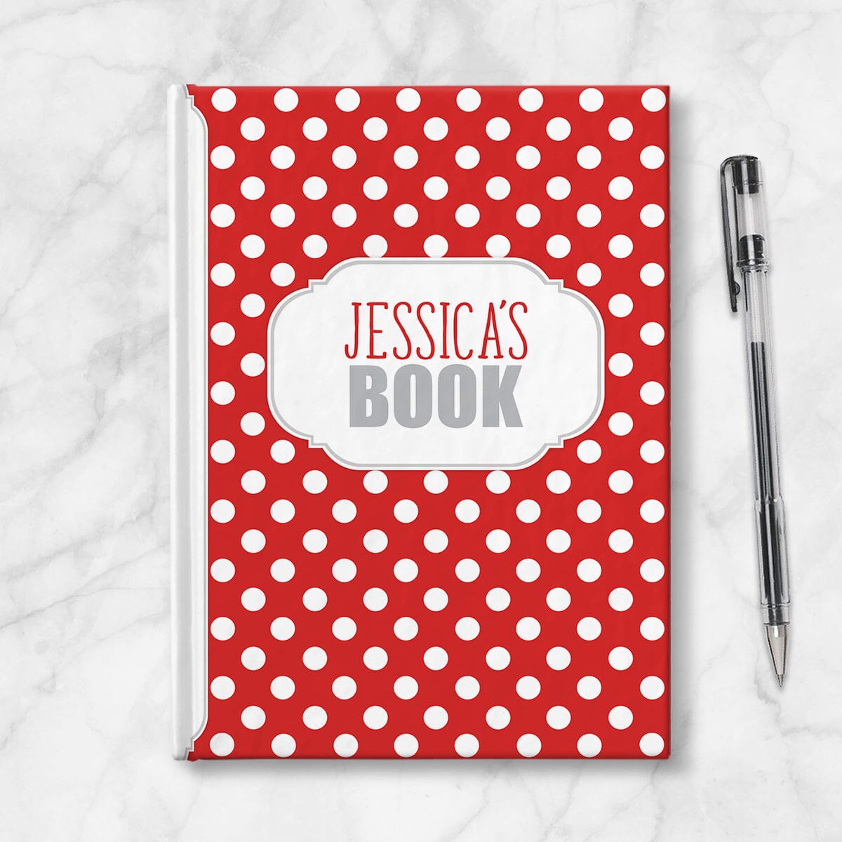 Personalized Red Polka Dot Journal at Artistically Invited. Image shows the book on a countertop next to a pen.