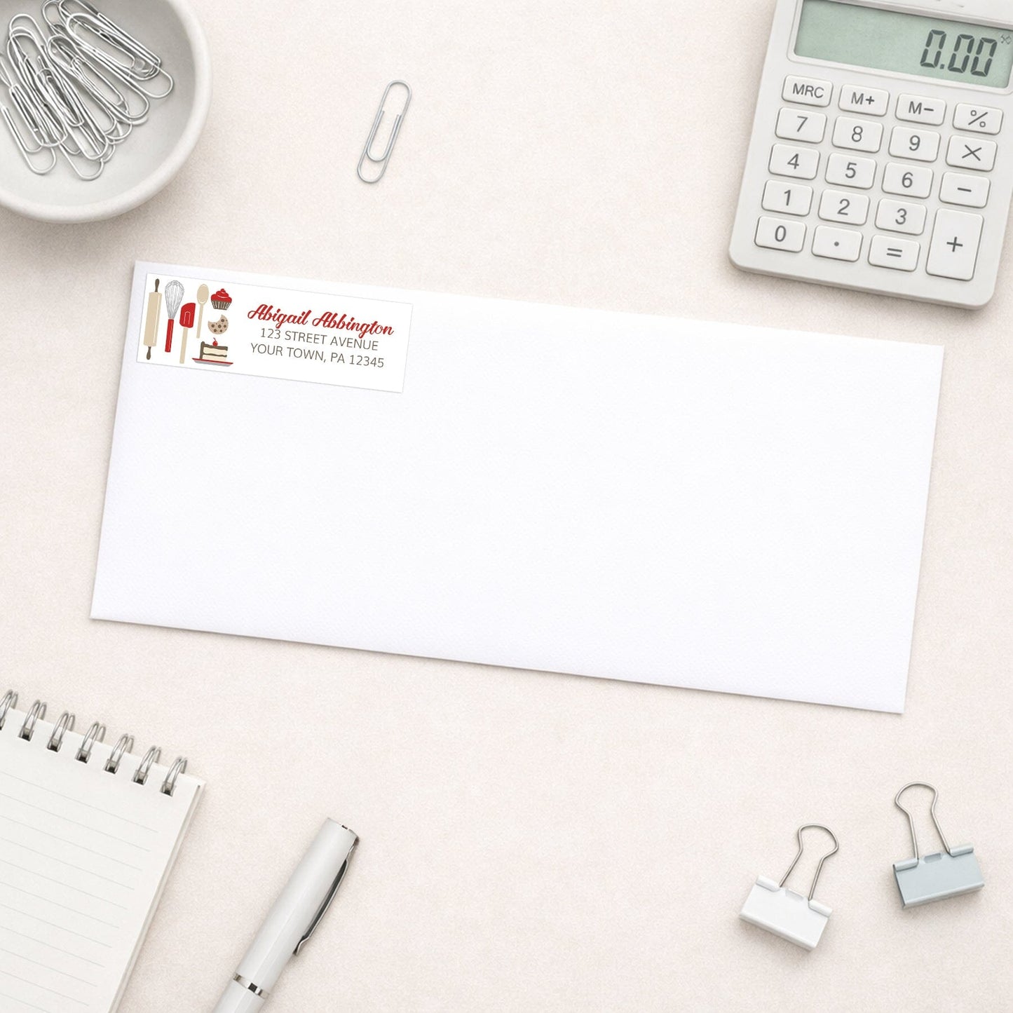 Red Baking Address Label shown on a white envelope with office supplies