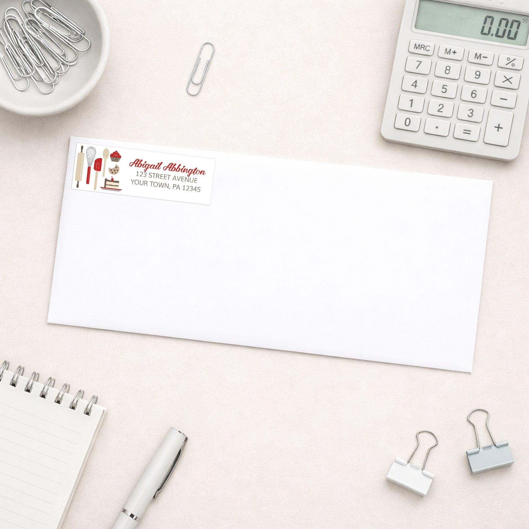 Red Baking Address Label shown on a white envelope with office supplies