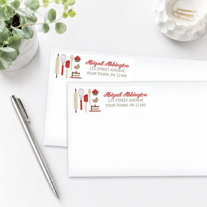 Red Baking Address Labels shown on white envelopes, on a white surface with a plant and a pen.