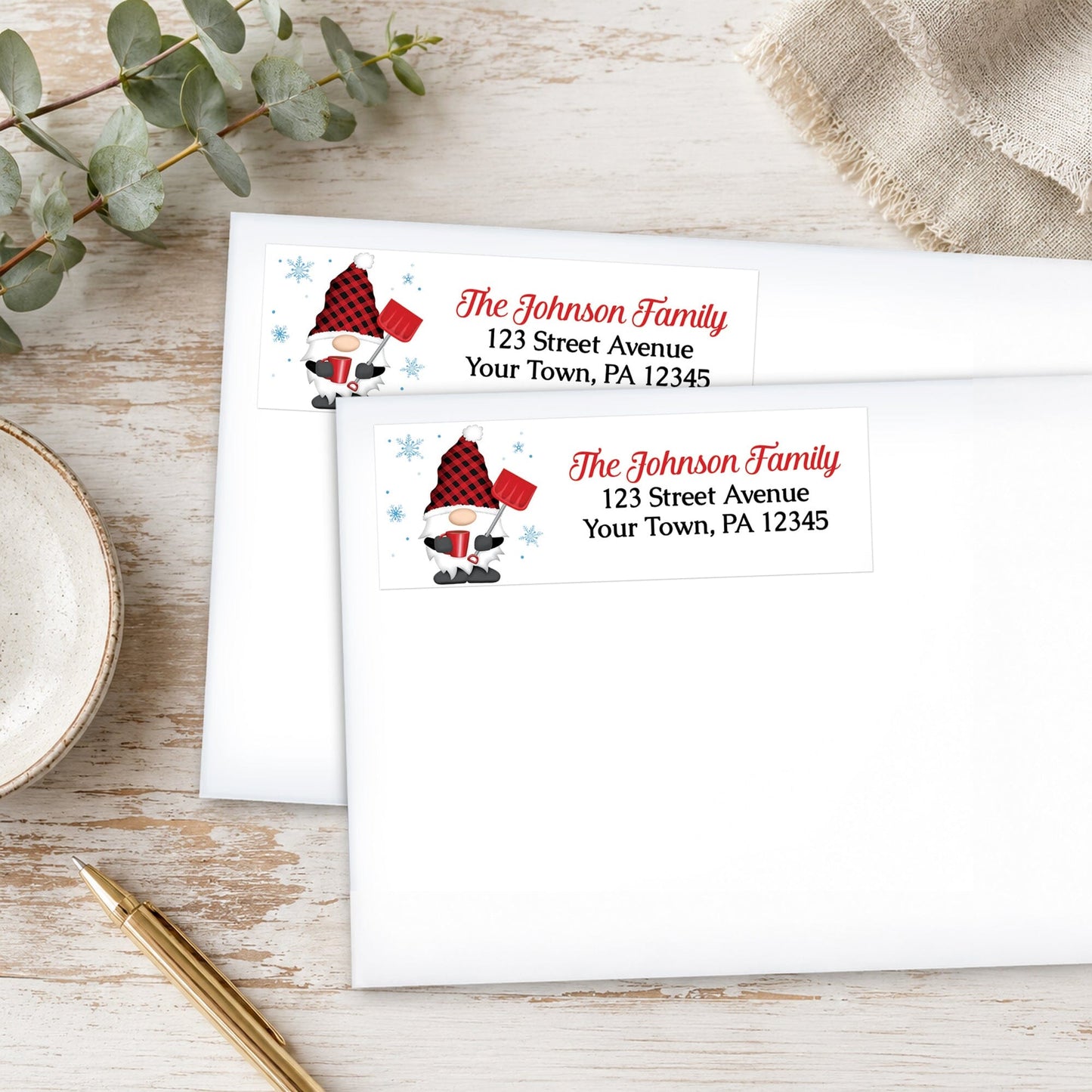 Red Buffalo Plaid Gnome Address Labels on white envelopes, shown on a wooden surface with eucalyptus leaves and a pen.