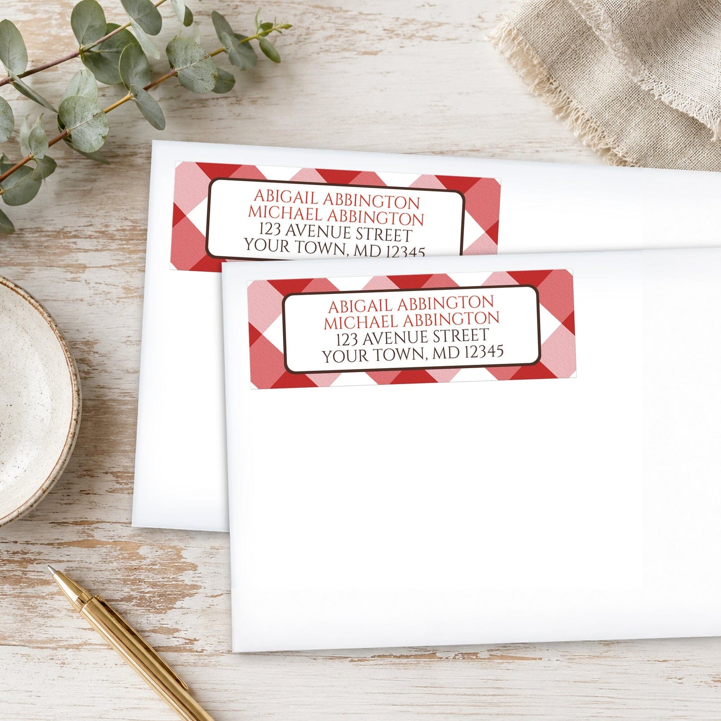 Personalized Red Gingham Address Labels on white envelopes with decorative elements on a wooden surface.