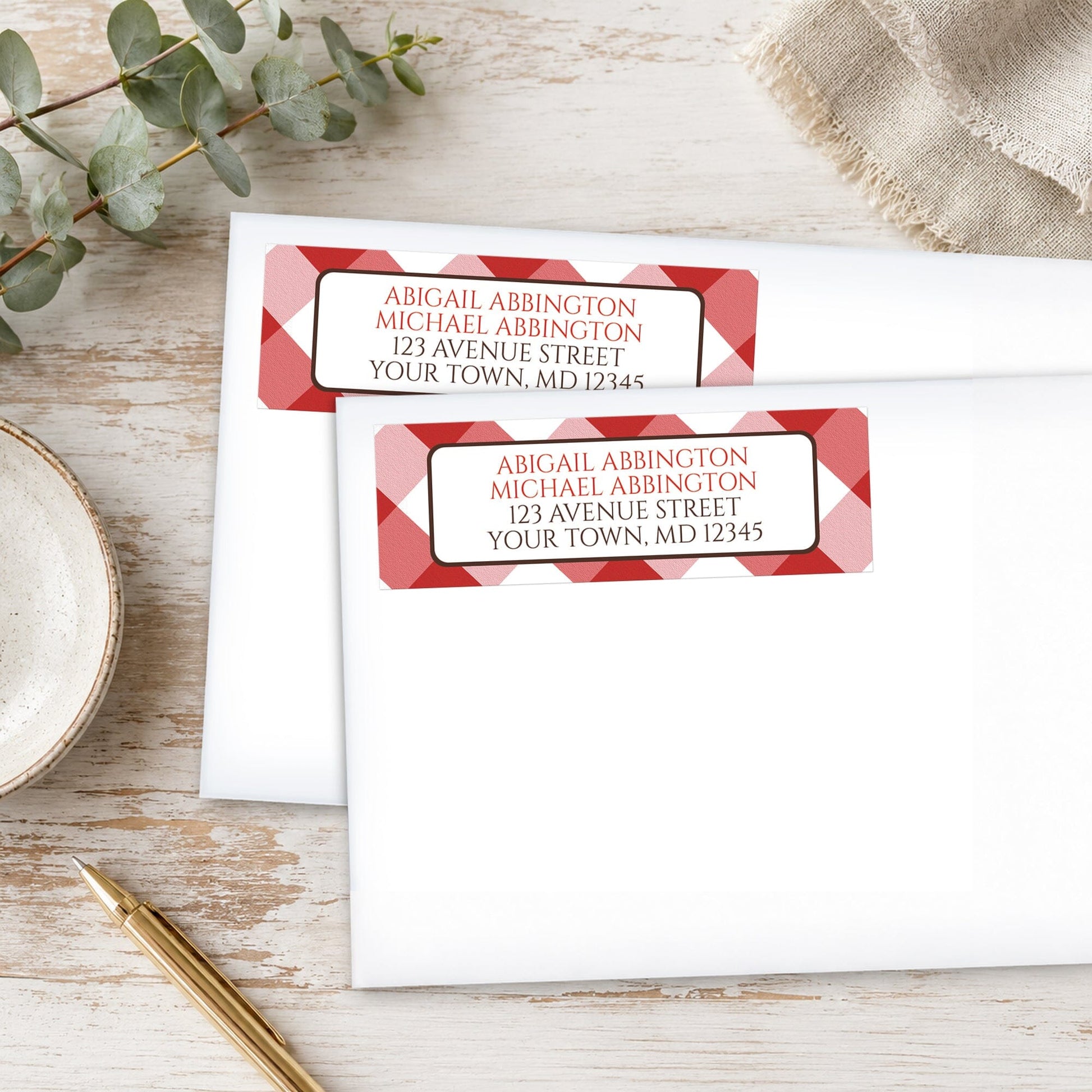 Personalized Red Gingham Address Labels on white envelopes with decorative elements on a wooden surface.