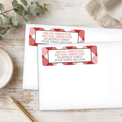 Personalized Red Gingham Address Labels on white envelopes with decorative elements on a wooden surface.