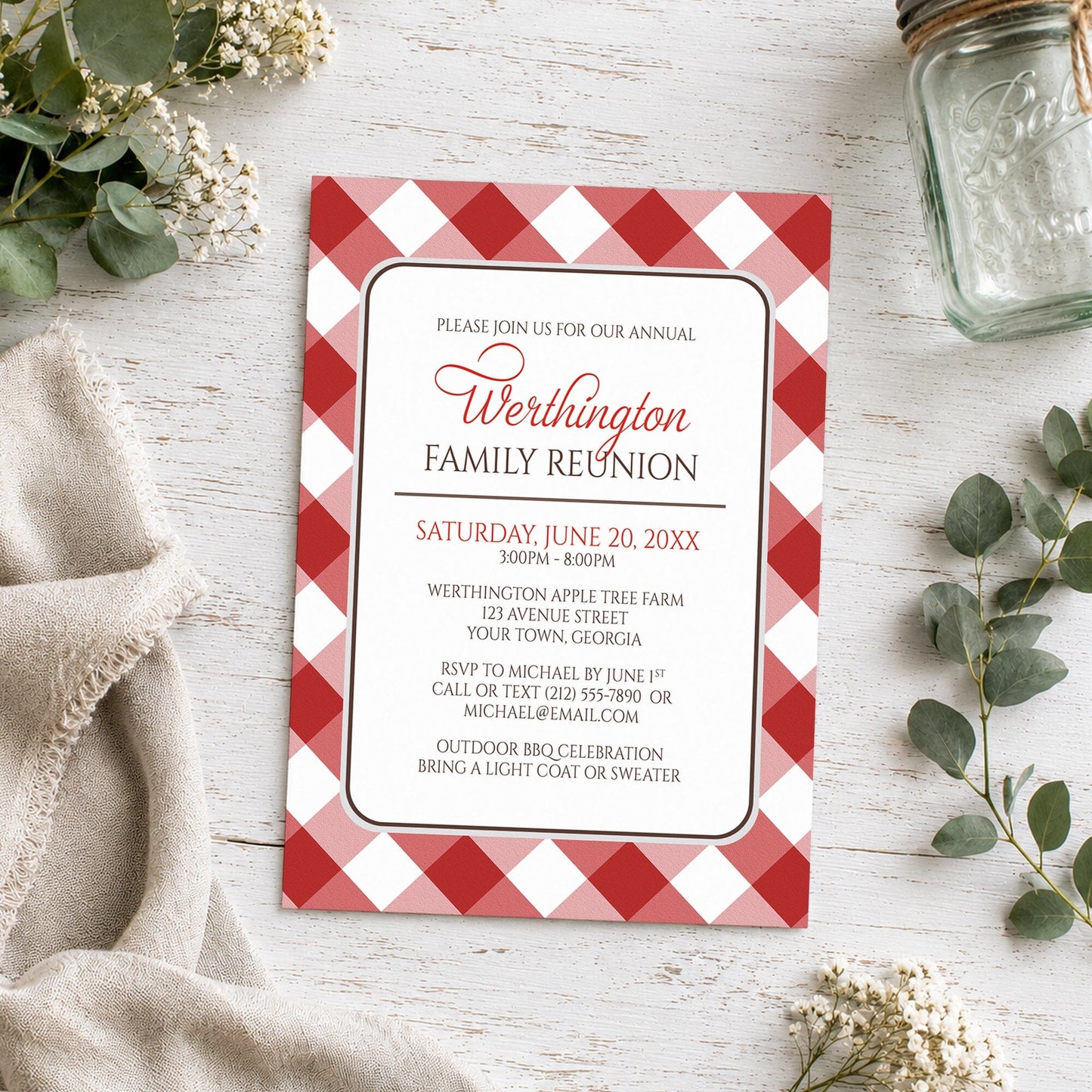 Red Gingham Family Reunion Invitation shown on a wooden surface with plants and a mason jar.