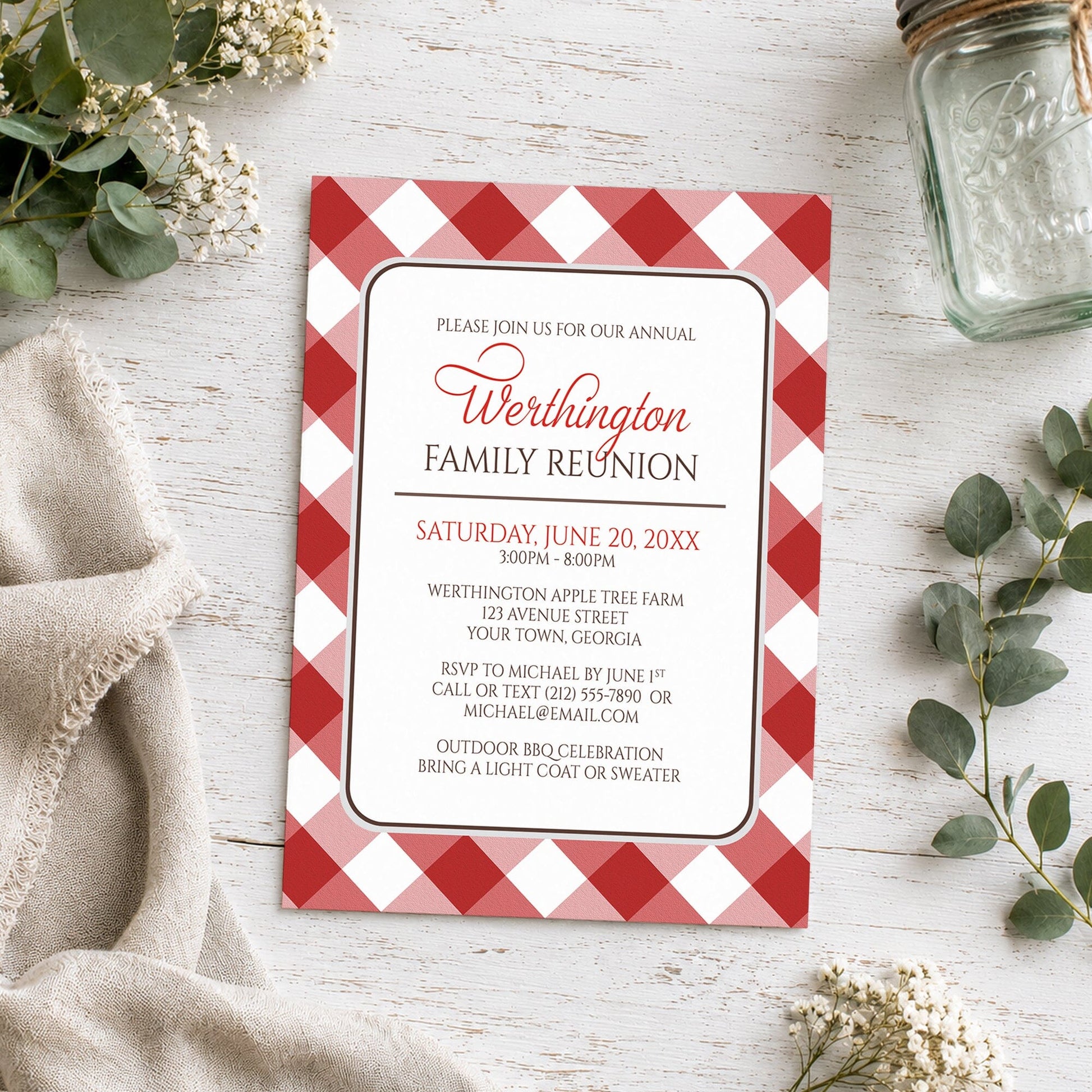 Red Gingham Family Reunion Invitation shown on a wooden surface with plants and a mason jar.
