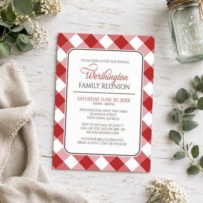 Red Gingham Family Reunion Invitation shown on a wooden surface with plants and a mason jar.