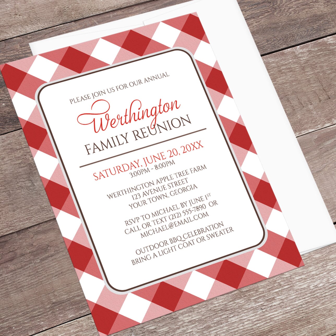 Red Gingham Family Reunion Invitation shown at an angle on a wooden surface with a white envelope.