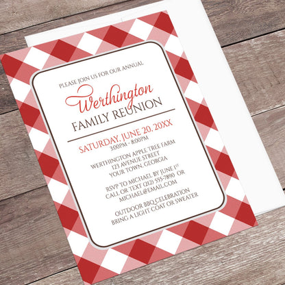 Red Gingham Family Reunion Invitation shown at an angle on a wooden surface with a white envelope.