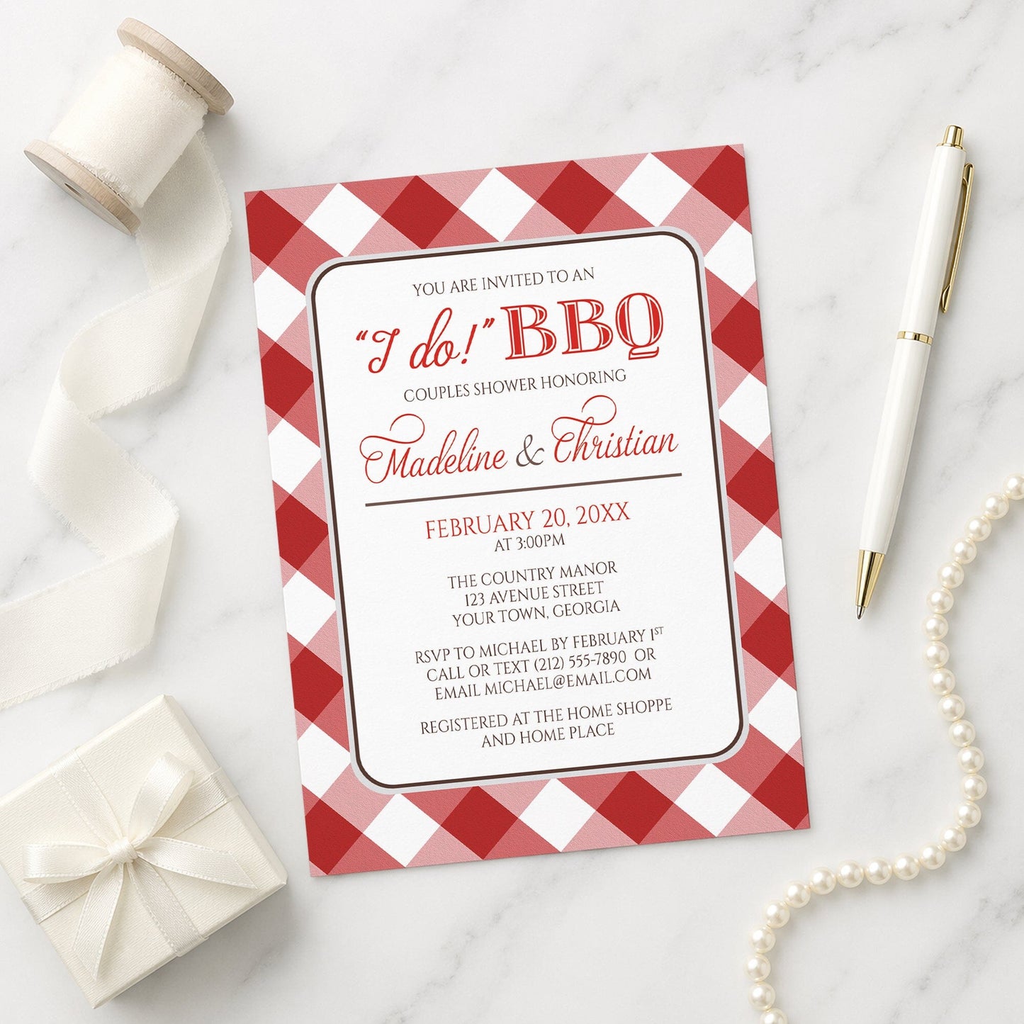 Red Gingham I Do BBQ Couples Shower Invitation shown on a marble surface with a white gift box, ribbon, pen, and pearls.