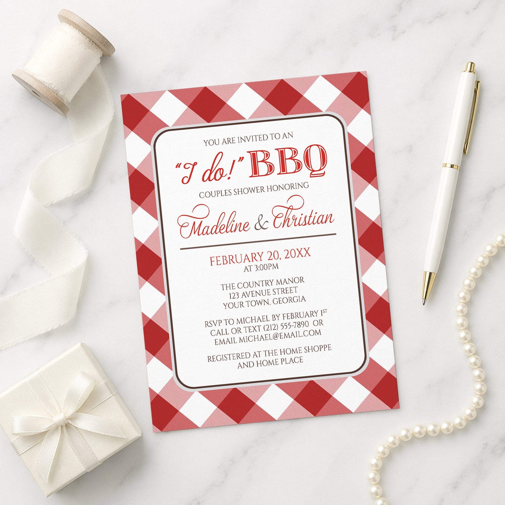 Red Gingham I Do BBQ Couples Shower Invitation shown on a marble surface with a white gift box, ribbon, pen, and pearls.