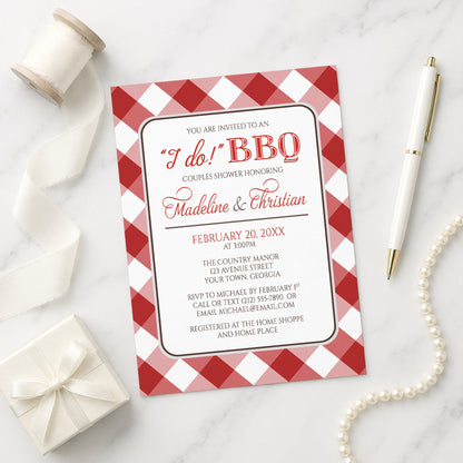 Red Gingham I Do BBQ Couples Shower Invitation shown on a marble surface with a white gift box, ribbon, pen, and pearls.