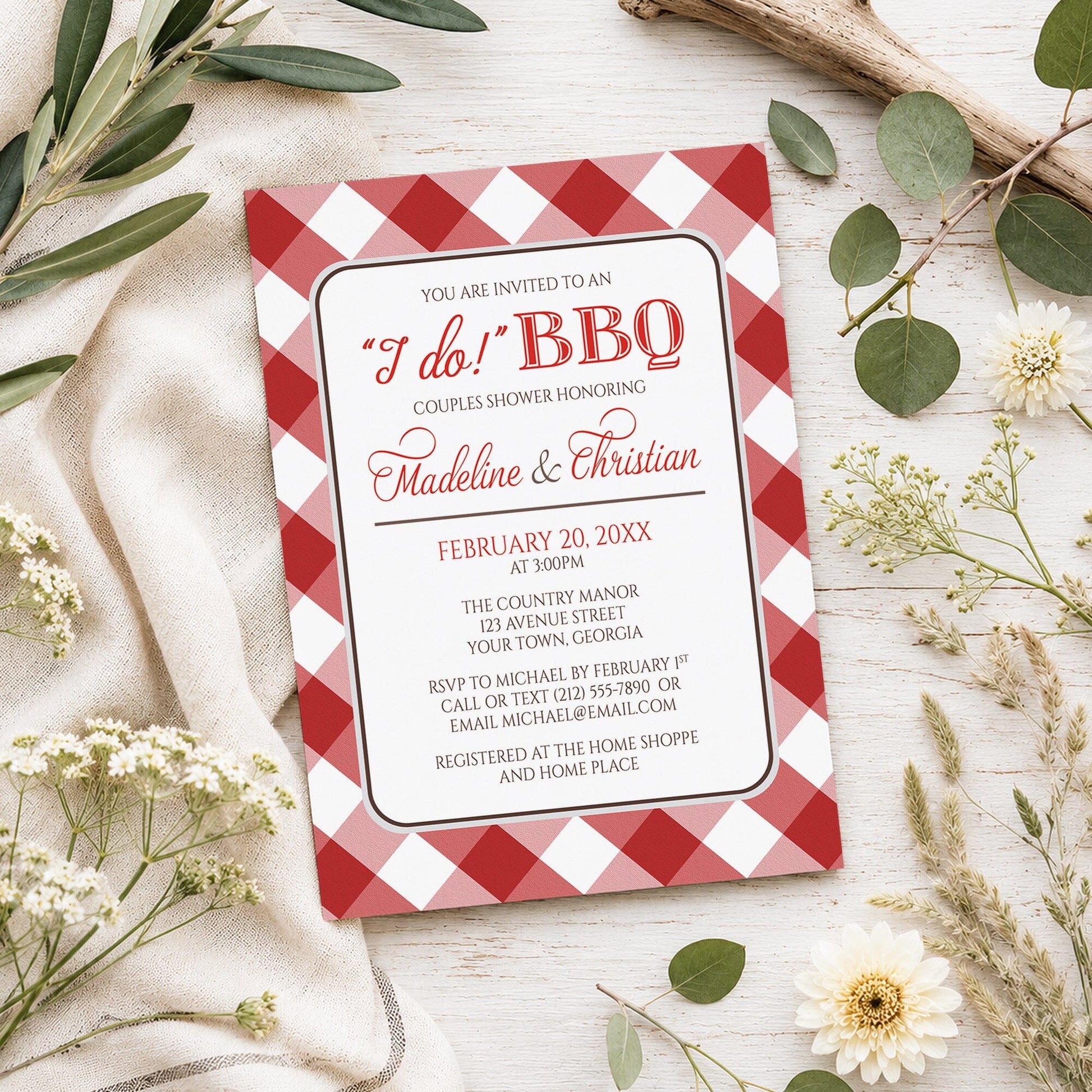 Red Gingham I Do BBQ Couples Shower Invitation shown on a light wooden surface with spring and summer plants.