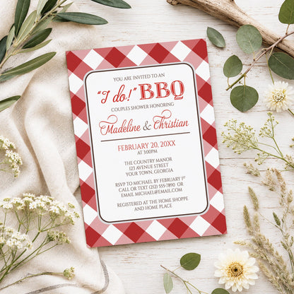 Red Gingham I Do BBQ Couples Shower Invitation shown on a light wooden surface with spring and summer plants.