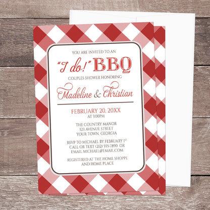 Red Gingham I Do BBQ Couples Shower Invitation shown on a brown wood surface with a white envelope.