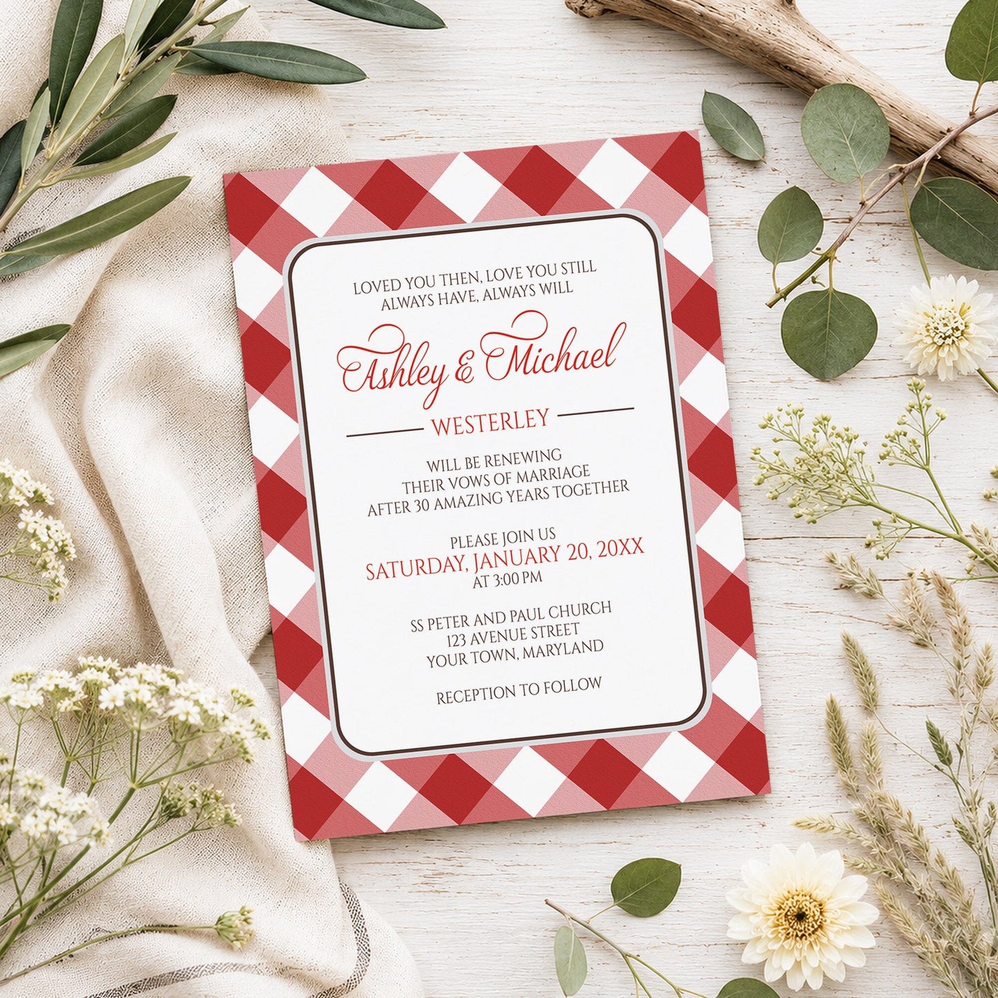 Red Gingham Vow Renewal Invitation shown on a light wooden surface with spring and summer plants.