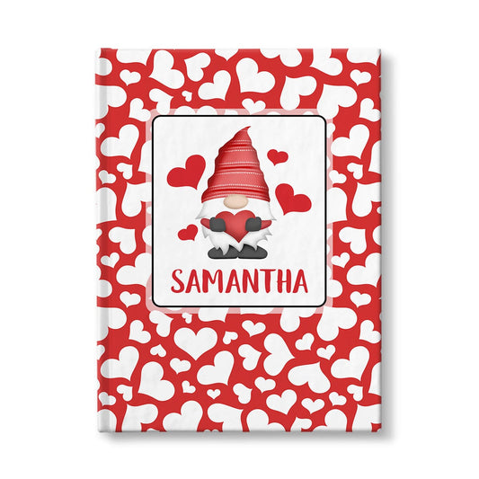 Personalized Red Hearts Gnome Journal at Artistically Invited. A custom book designed with an adorable gnome holding a red heart with 4 hearts floating around him in a white rectangular design on the front of the book, with your name personalized in red below the gnome. The background design that wraps around the cover of the book features a red background color filled with cute multi-directional white hearts of different sizes.