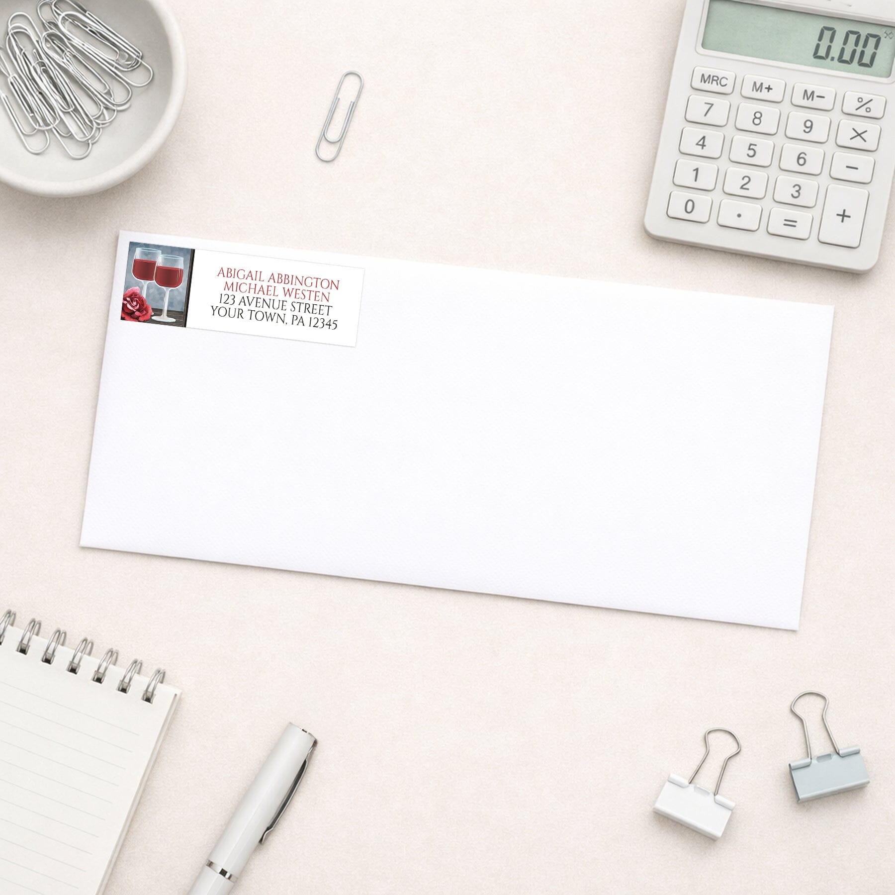 Red Wine Glasses Floral Rose Address Label shown on a white envelope with everyday office supplies