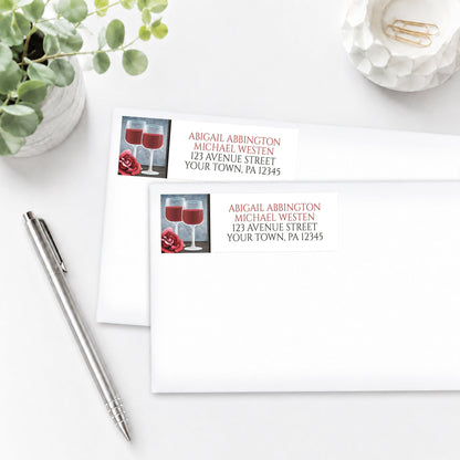 Red Wine Glasses Floral Rose Address Labels, shown on white envelopes, on a white surface with a pen and plant beside them.