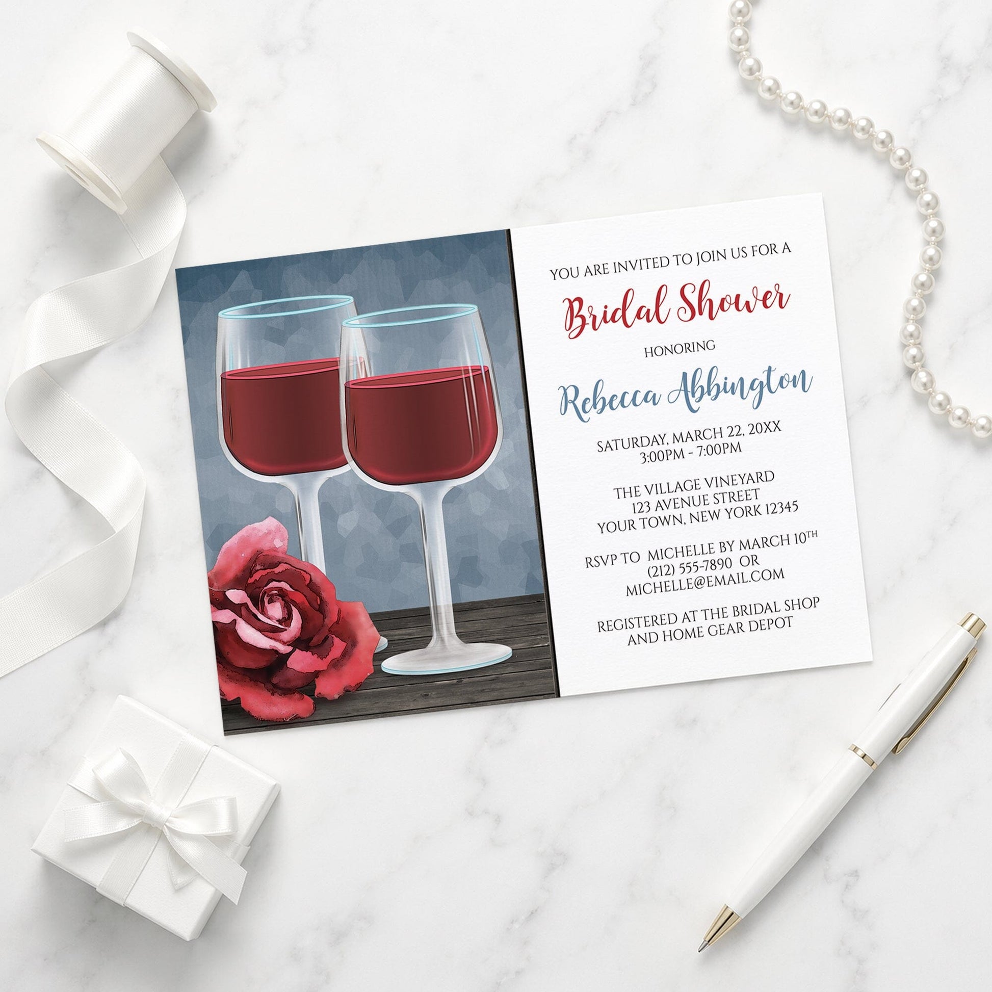 Red Wine Glasses Floral Rose Bridal Shower Invitation on a marble surface with a white gift box, ribbon, pen, and pearls.