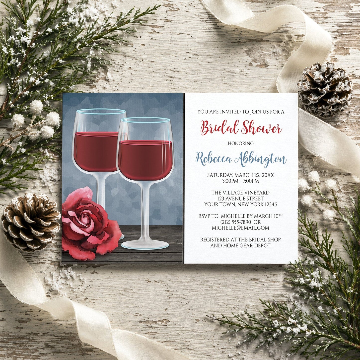 Red Wine Glasses Floral Rose Bridal Shower Invitation on a rustic wood surface with winter pine cones and ribbon.