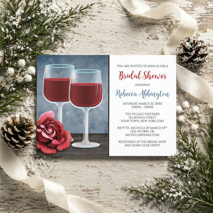 Red Wine Glasses Floral Rose Bridal Shower Invitation on a rustic wood surface with winter pine cones and ribbon.