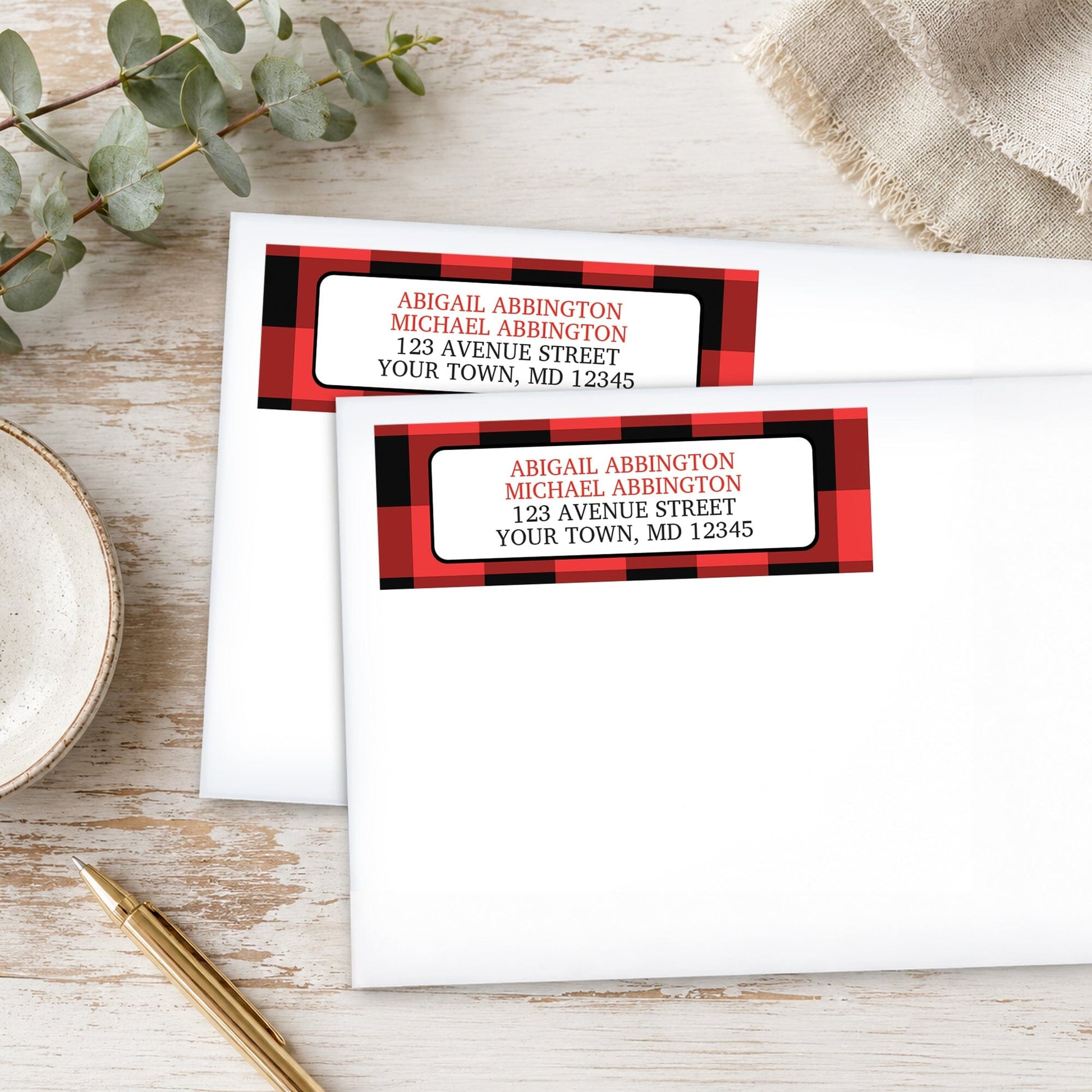 Red and Black Buffalo Plaid Address Labels on white envelopes, shown on a wooden surface with plants and a pen.