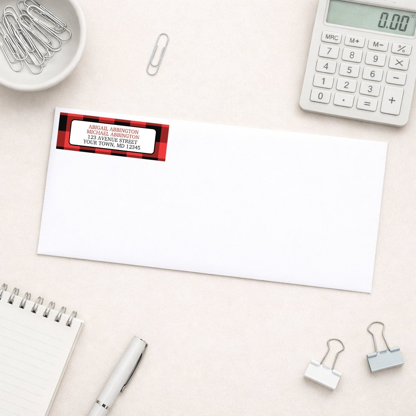 Red and Black Buffalo Plaid Address Label shown on a white envelope with everyday office supplies