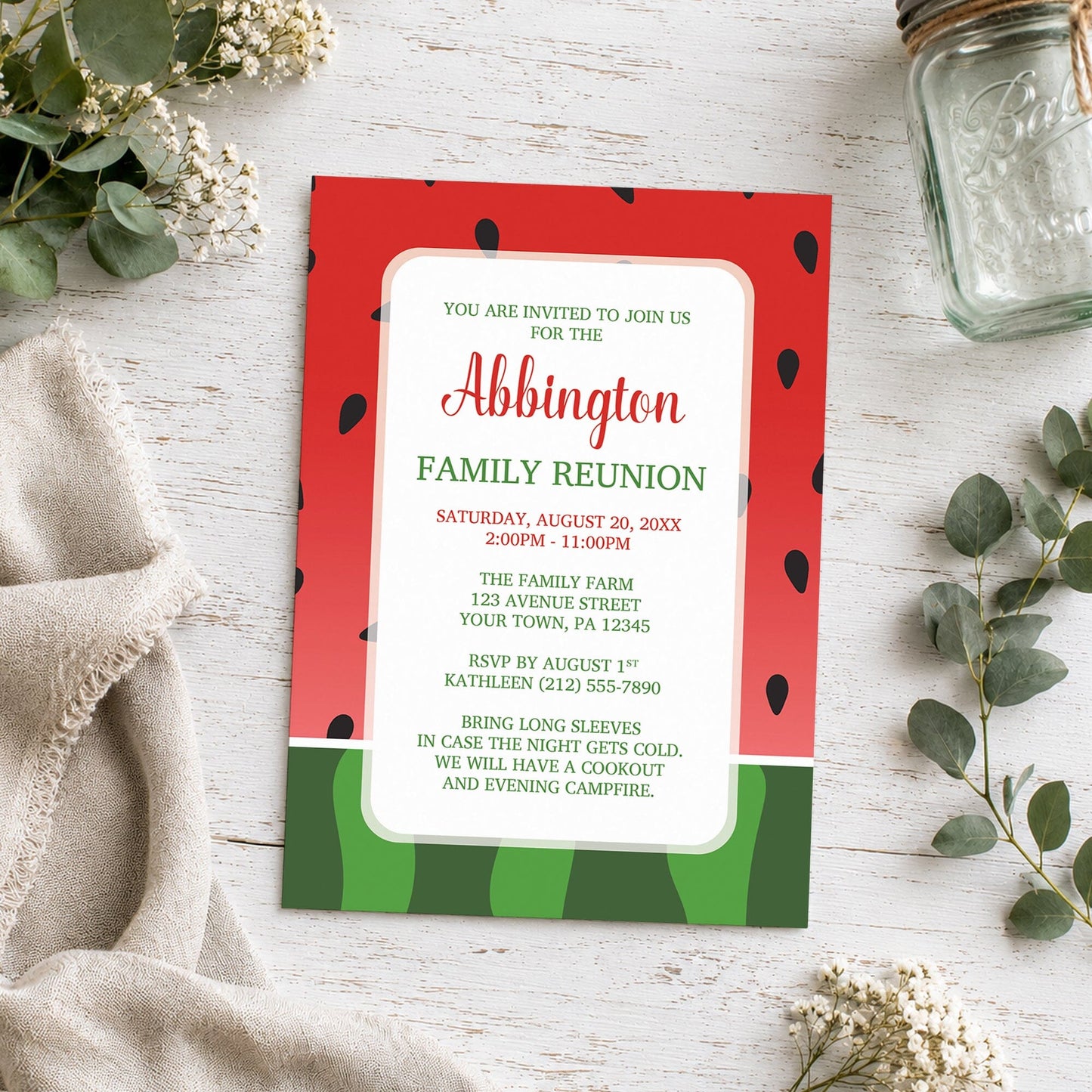 Red and Green Watermelon Family Reunion Invitation shown on a wooden surface with plants and a small mason jar.