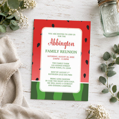 Red and Green Watermelon Family Reunion Invitation shown on a wooden surface with plants and a small mason jar.