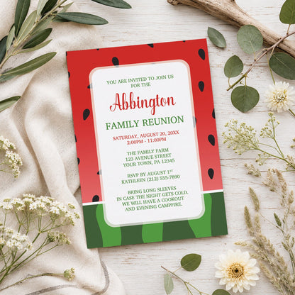 Red and Green Watermelon Family Reunion Invitation shown on a wooden surface with spring and summer plants.