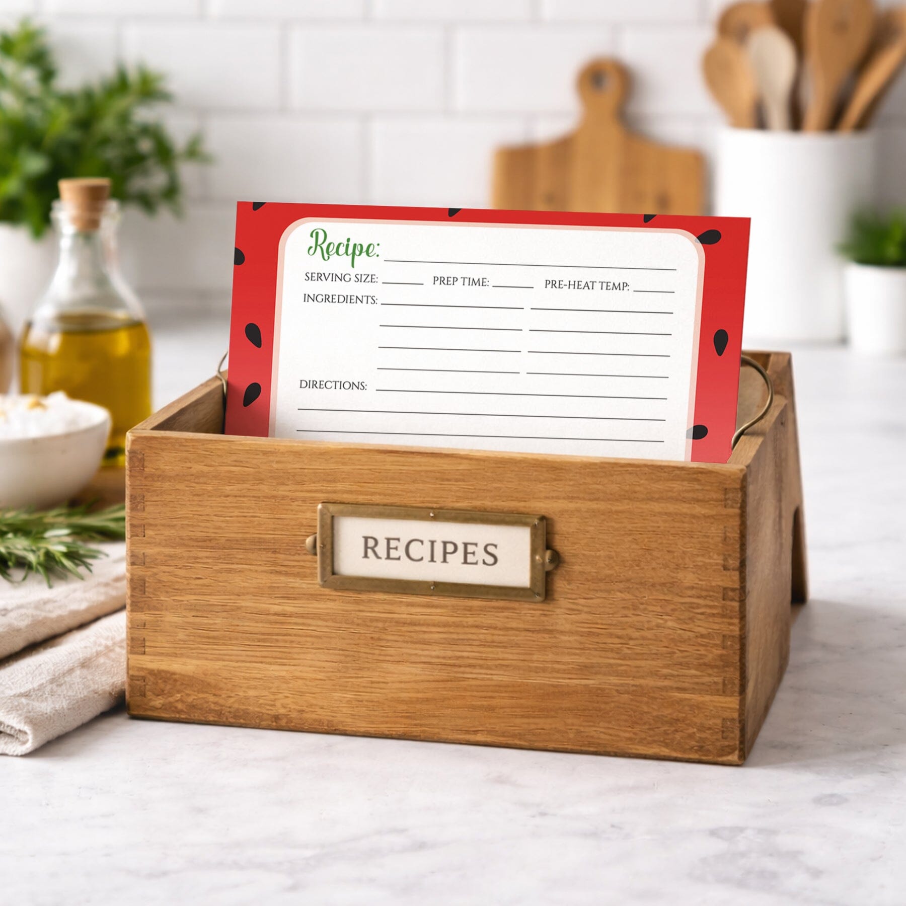 Wooden recipe box with a Red and Green Watermelon Recipe Card inside on a kitchen counter