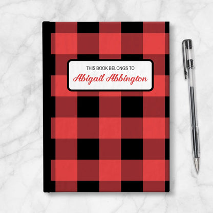 Personalized Red and Black Buffalo Plaid Journal at Artistically Invited. Image shows the book on a countertop with a pen next to it.