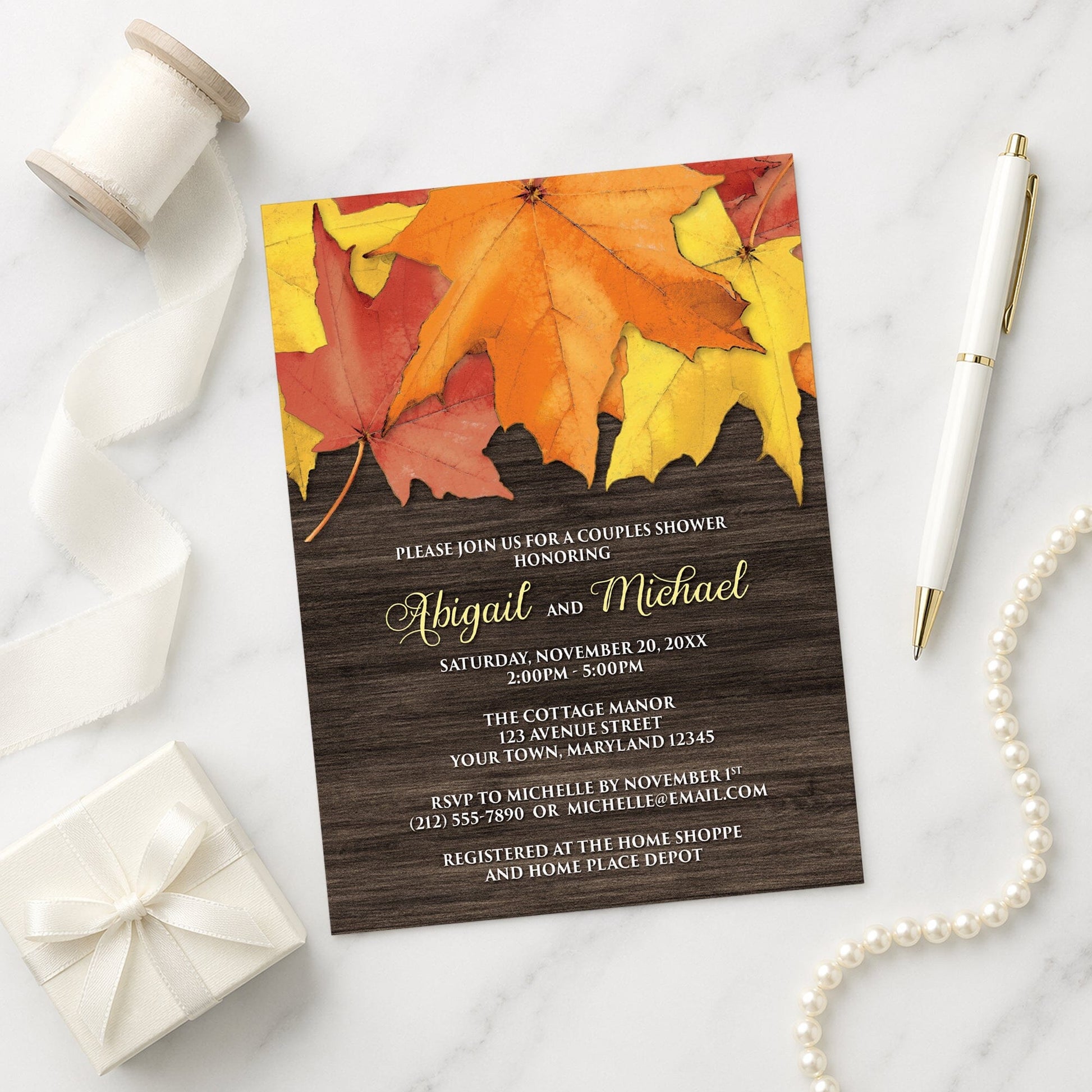 Rustic Autumn Leaves Wood Couples Shower Invitation shown on a marble surface with a white gift box, pen, ribbon, and pearls.