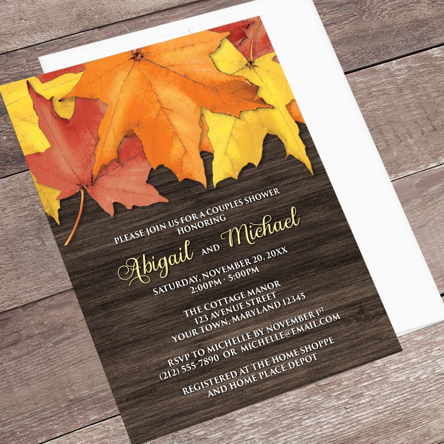 Rustic Autumn Leaves Wood Couples Shower Invitation shown at an angle on a brown wood surface with a white envelope.