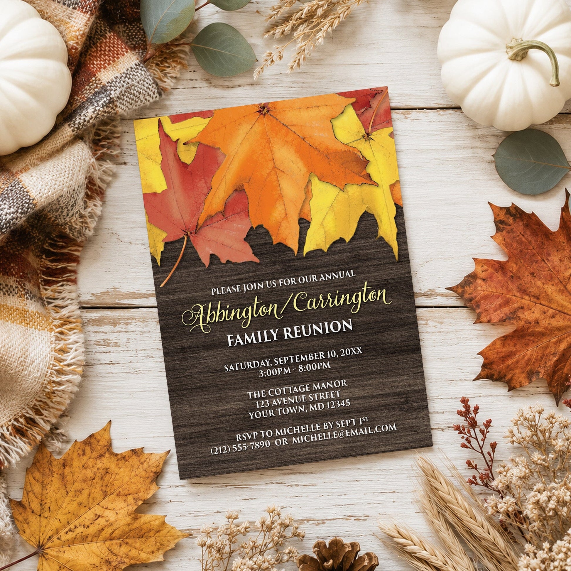 Rustic Autumn Leaves Wood Family Reunion Invitation on a light wooden surface with fall leaves and autumn decor.