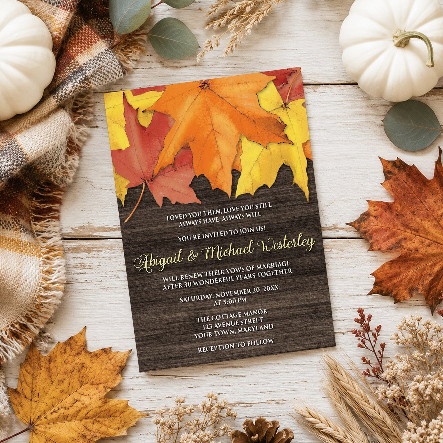 Rustic Autumn Leaves Wood Vow Renewal Invitation shown on a wooden surface with fall leaves and autumn decor.
