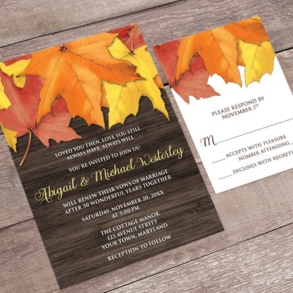 Rustic Autumn Leaves Wood Vow Renewal Invitation shown at an angle on a brown wood surface with the matching RSVP card.