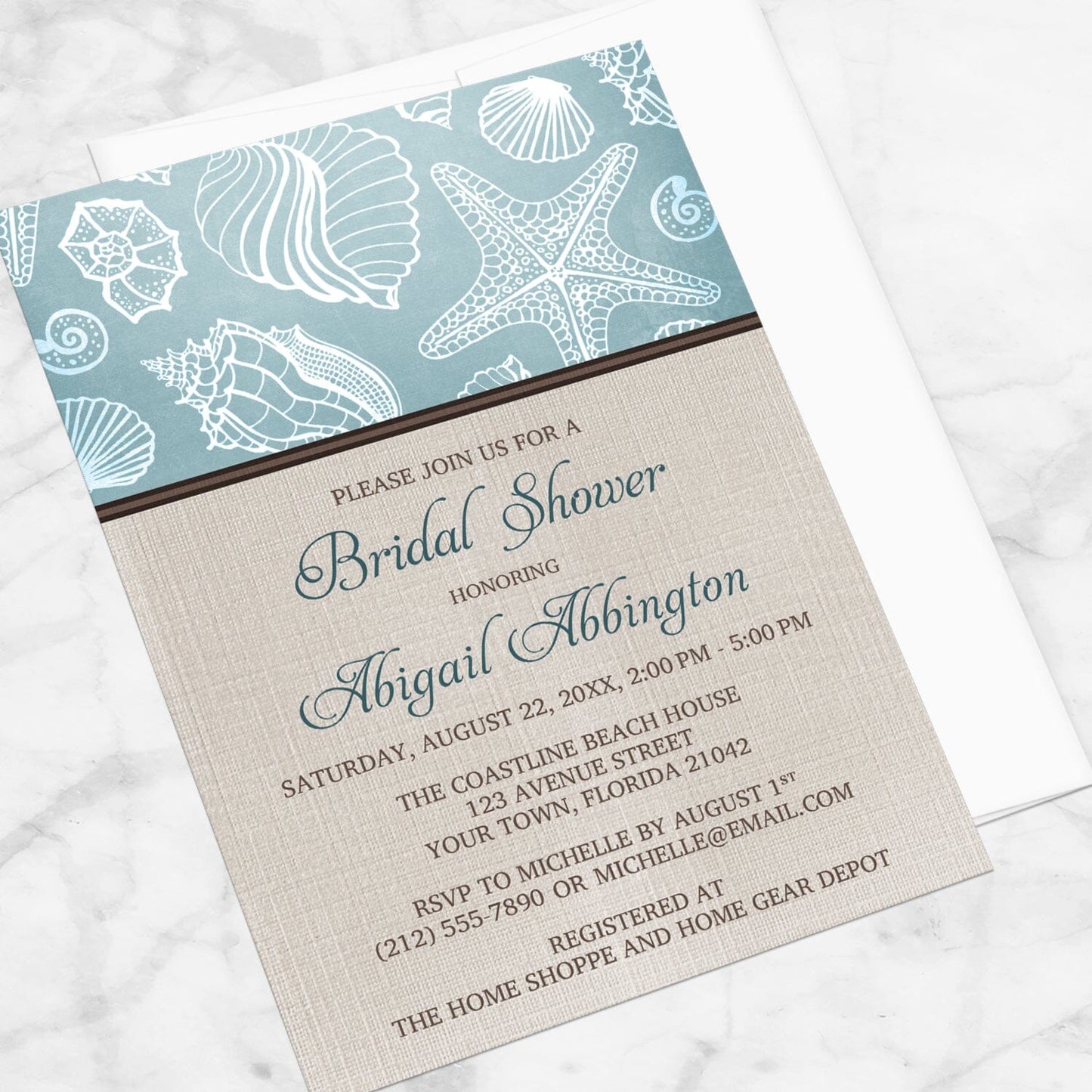 Rustic Beach Linen Seashell Bridal Shower Invitation shown at an angle on a marble surface with a white envelope.